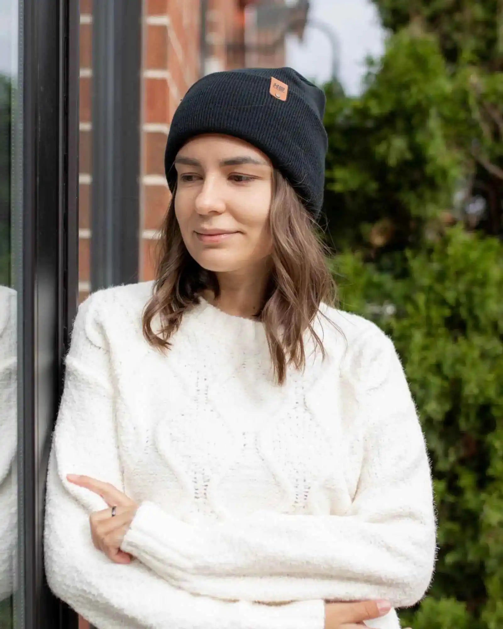 Charcoal black cuff beanie on person with small square logo patch on top
