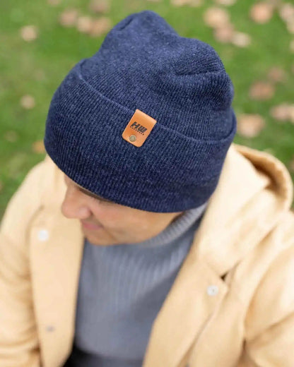 Denim blue beanie with folded cuff and tan logo patch, angled view