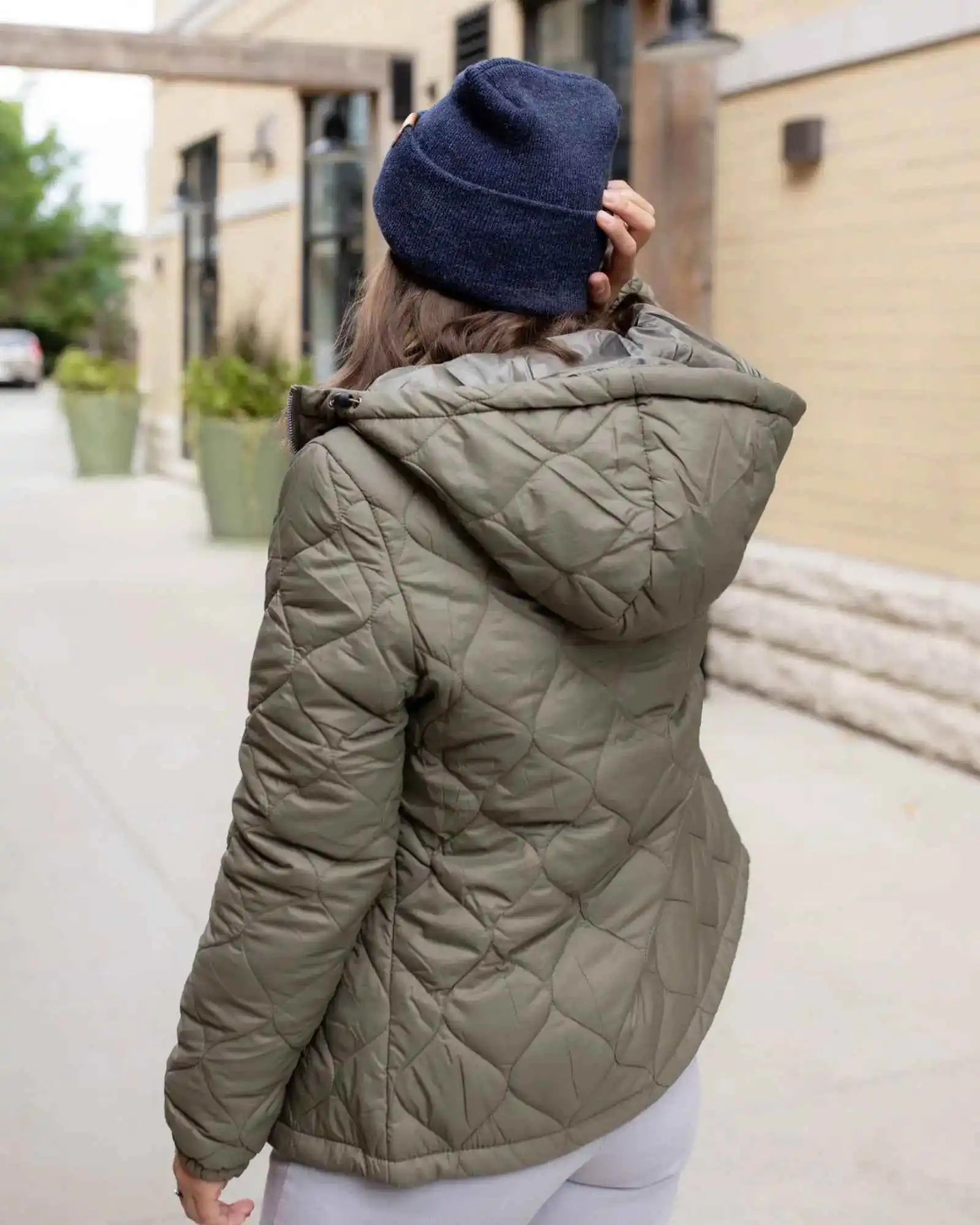 Denim blue beanie seen from the back, folded cuff and tan logo patch