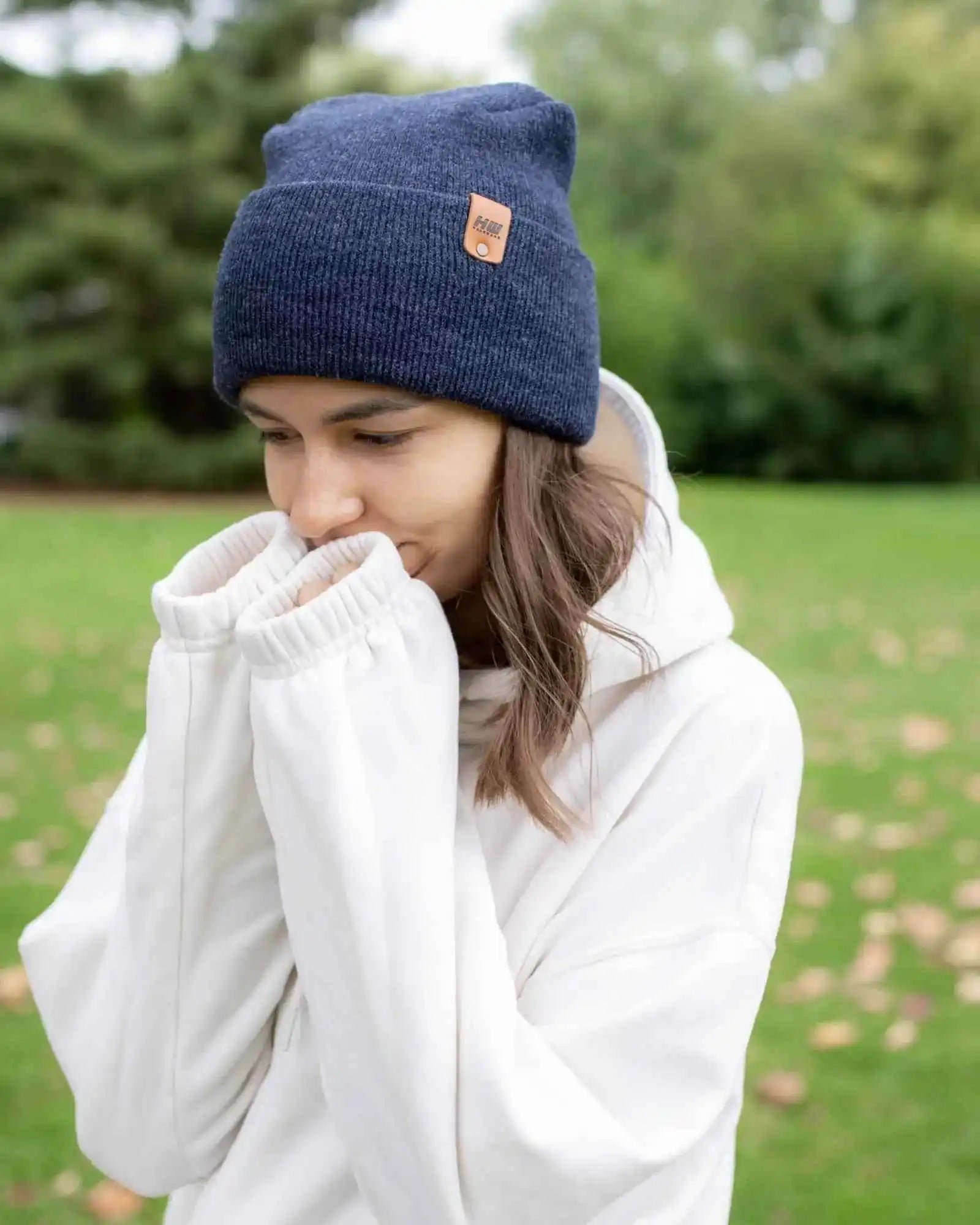 Denim blue cuffed knit beanie with tan logo patch, model wearing white hoodie