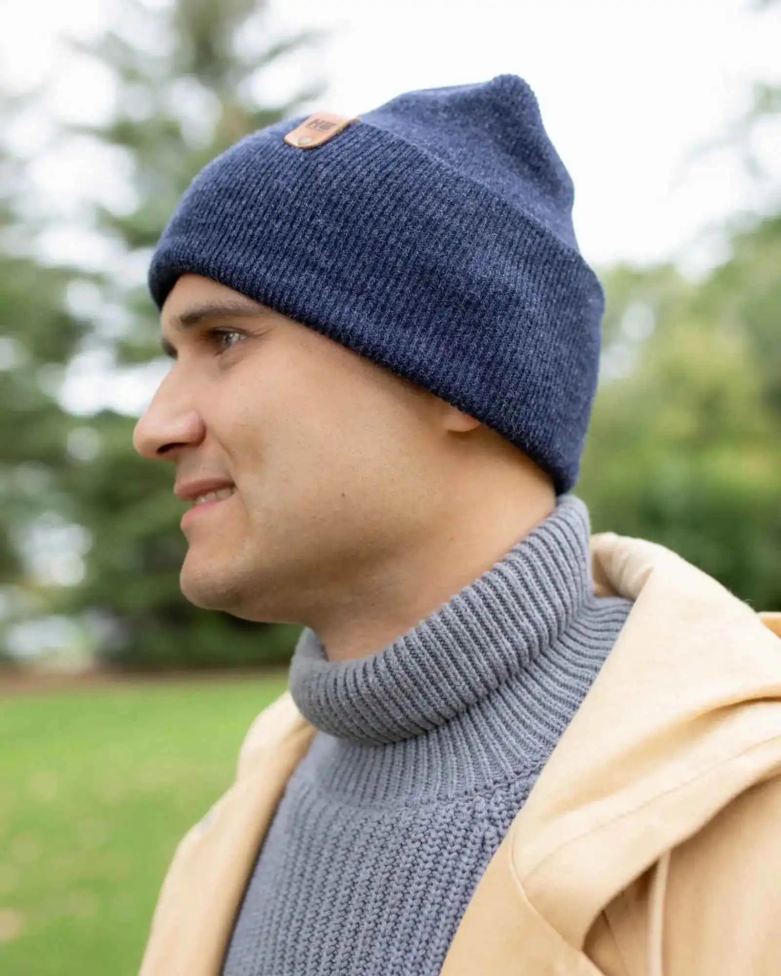 Denim blue beanie with turned cuff and tan logo patch, side view
