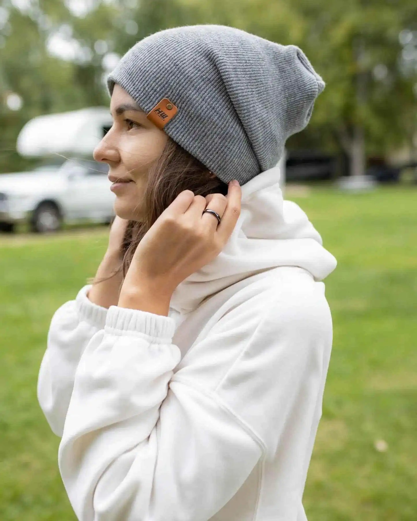 Gray cuffed beanie on head with small square logo patch near the foldover brim