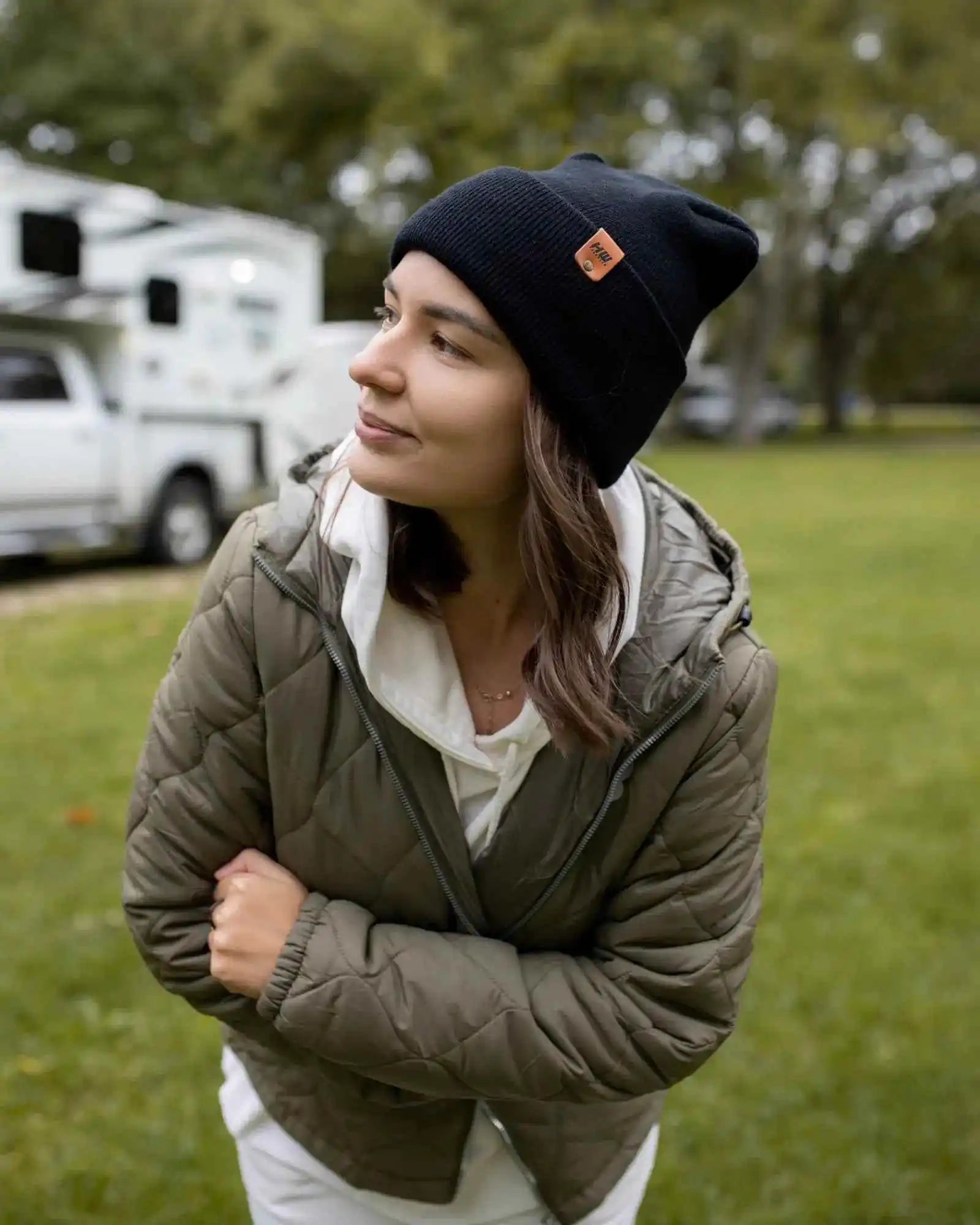 Midnight black knit beanie with orange logo patch, cuffed edge.