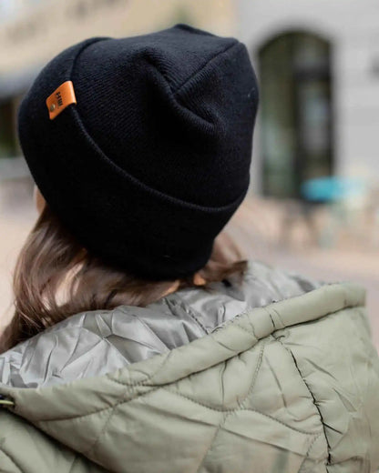 Midnight black knit beanie with orange logo patch on side seam.