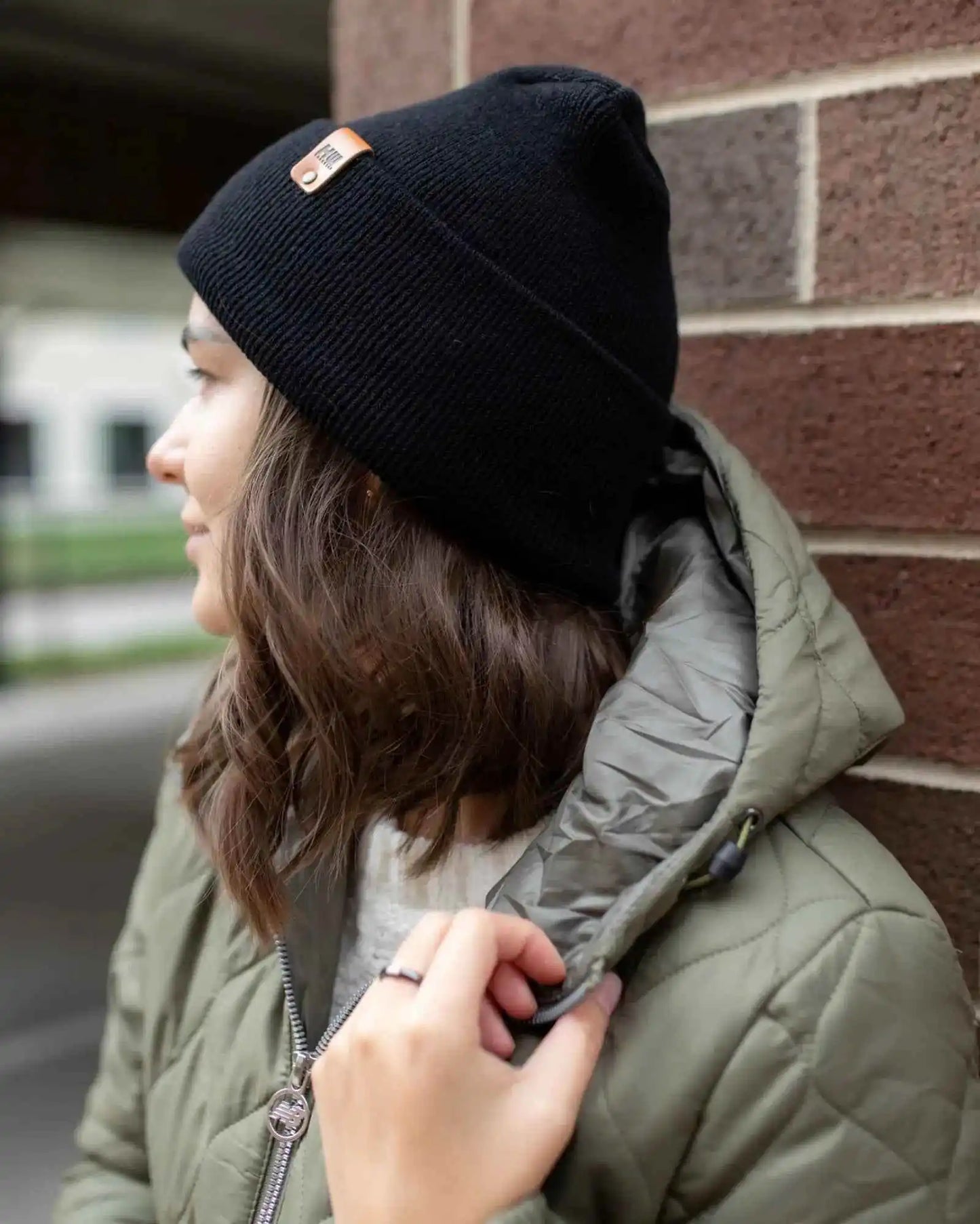 Midnight black cuffed knit beanie with orange logo patch on side.