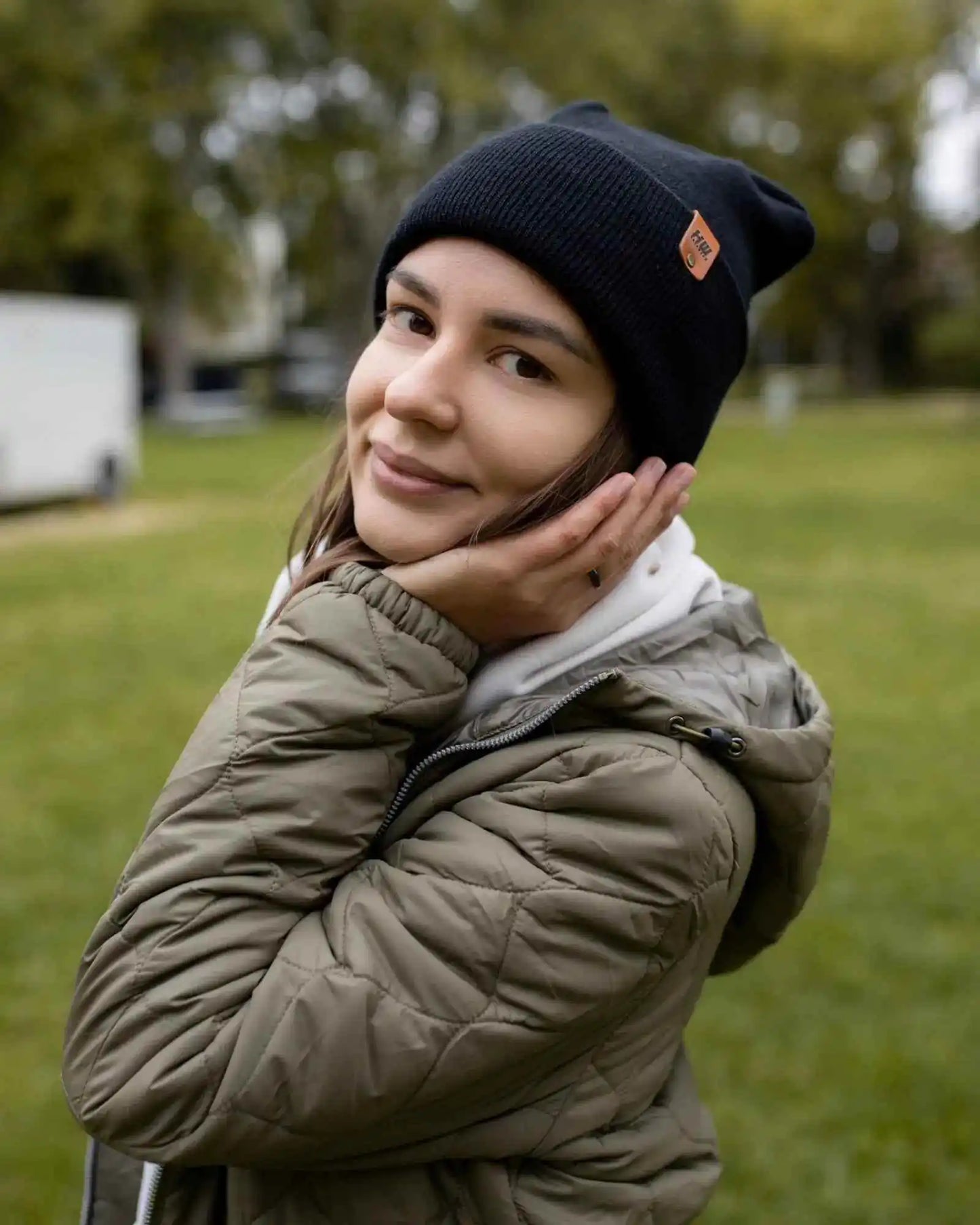 Midnight black knit beanie with orange logo patch on cuff.