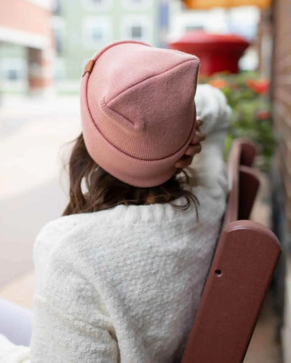 Pearl pink cuffed beanie with small square logo patch, back view from side