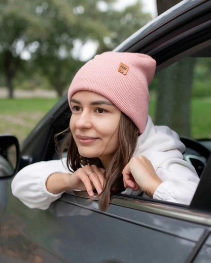 Pearl pink knit beanie with small square logo patch, worn while seated in car