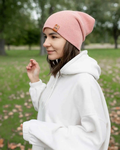Pearl pink cuffed beanie with small square logo patch, worn on head in profile