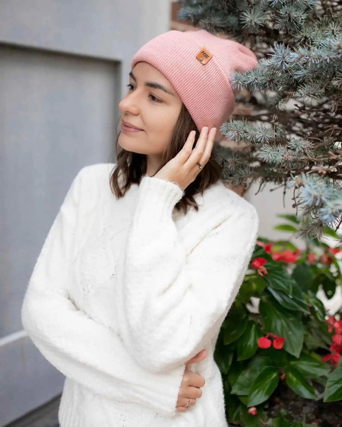 Pearl pink beanie with cuff and small square logo patch, worn and viewed from side