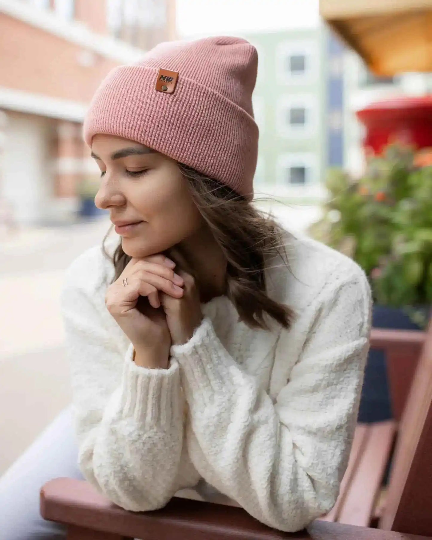 Pearl pink cuffed beanie with small square logo patch, worn on head
