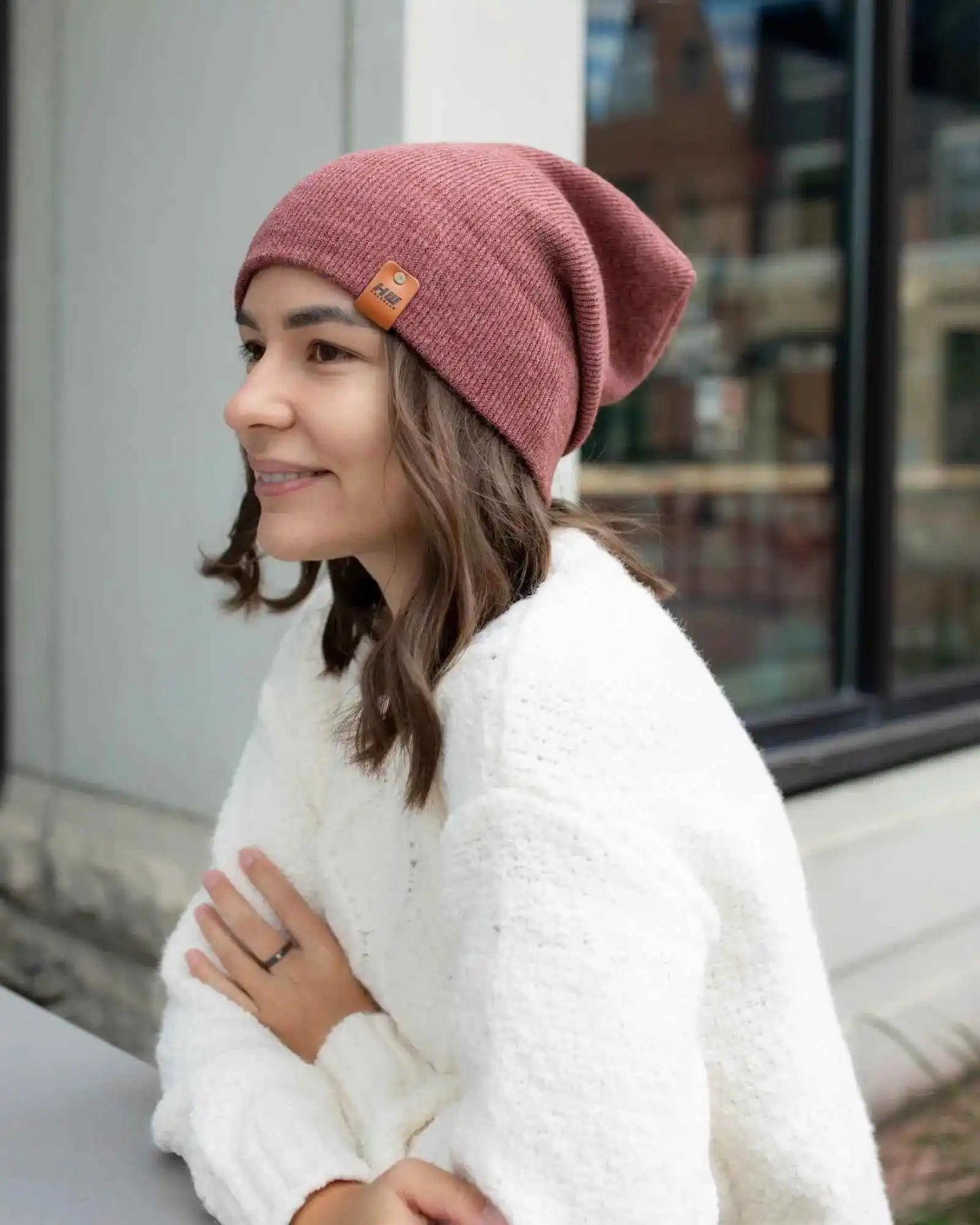 Rusty burgundy knit beanie with folded cuff and small logo patch on front
