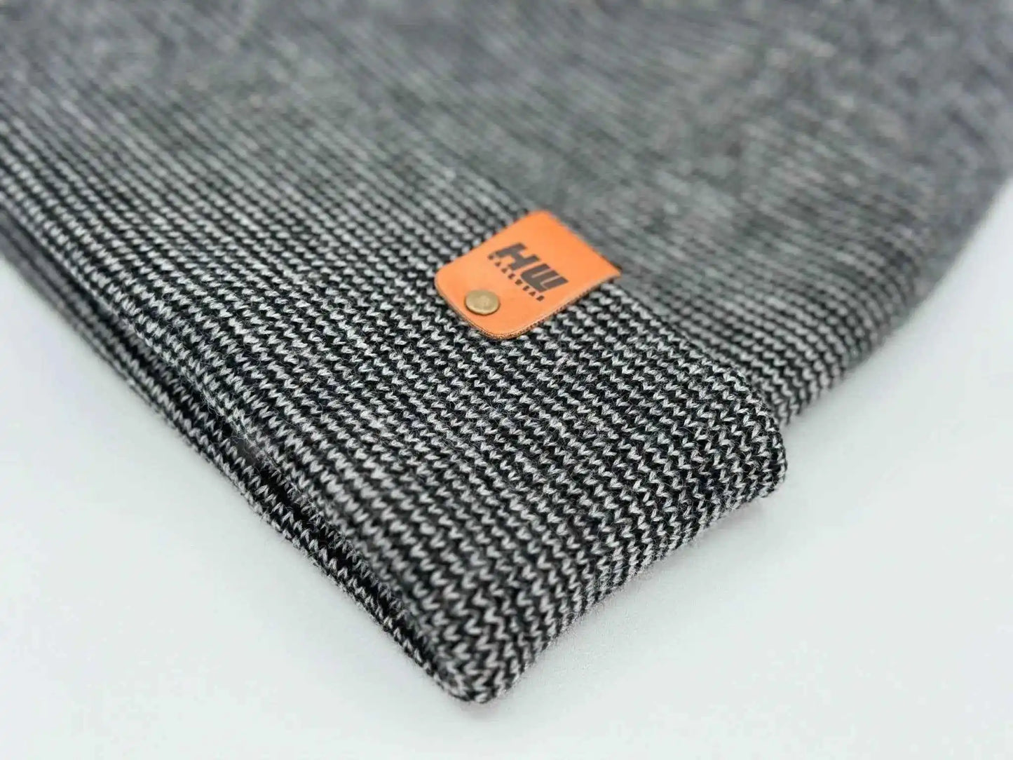 Folded cuffed beanie corner detail in dark gray knit with orange brand patch