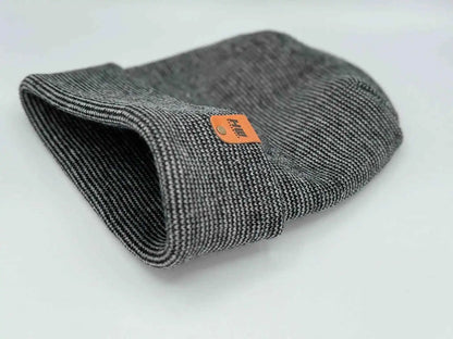 Cuffed beanie folded flat, dark gray knit with orange brand label at center