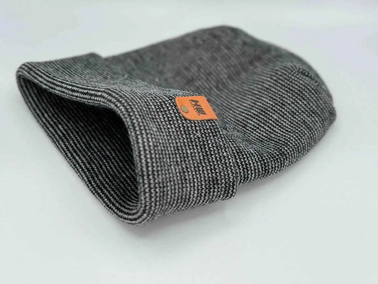 Cuffed beanie folded flat, dark gray knit with orange brand label at center