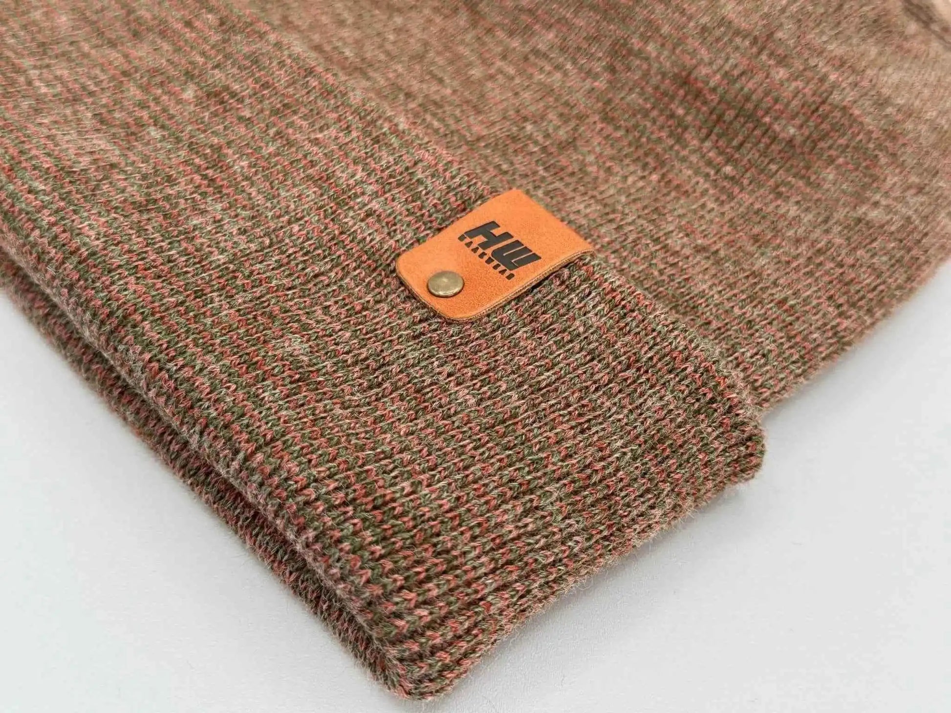 Brown knit beanie close-up with leather logo patch on cuff