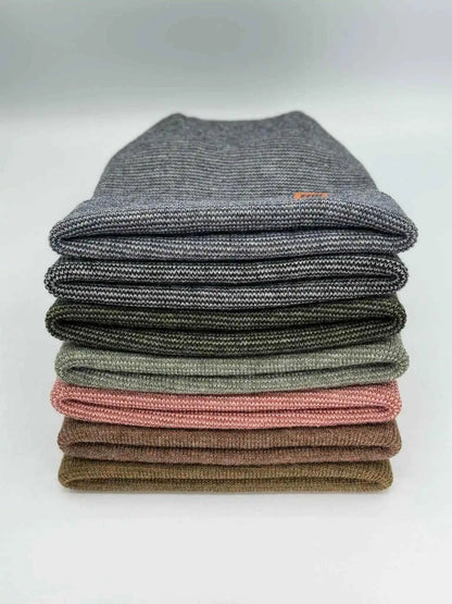 Stack of cuffed beanies in mixed knit colors, folded with logo patches
