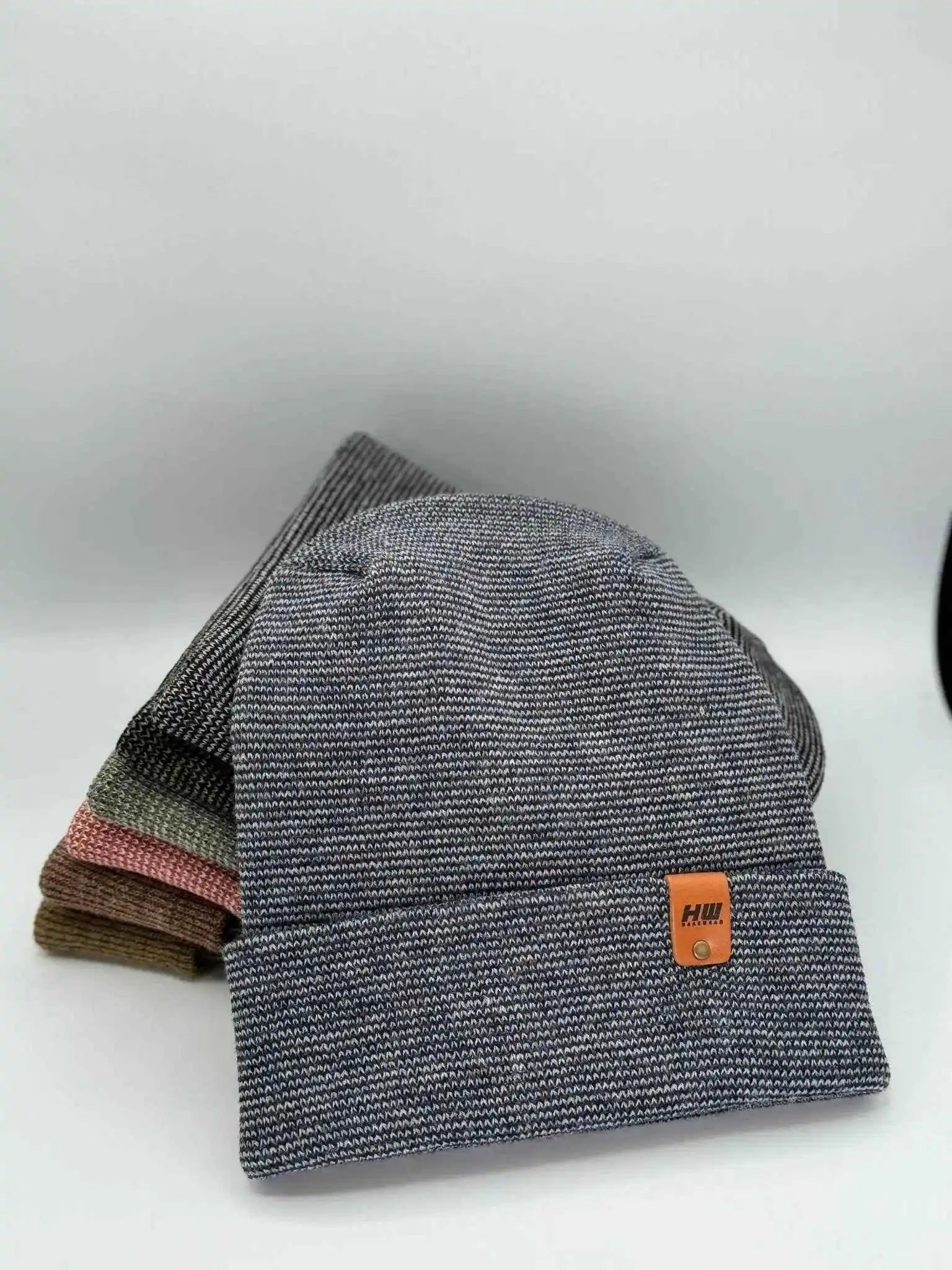 Gray cuffed beanie with orange logo patch and denim blue inner layer