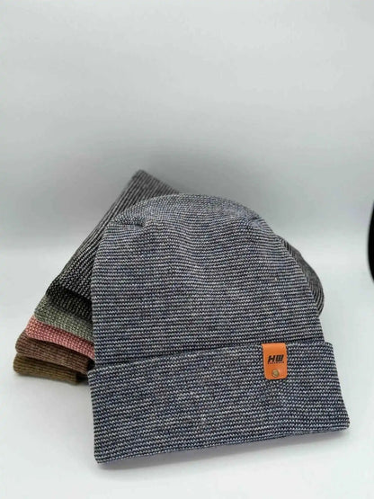 Gray cuffed beanie with orange logo patch and denim blue inner layer