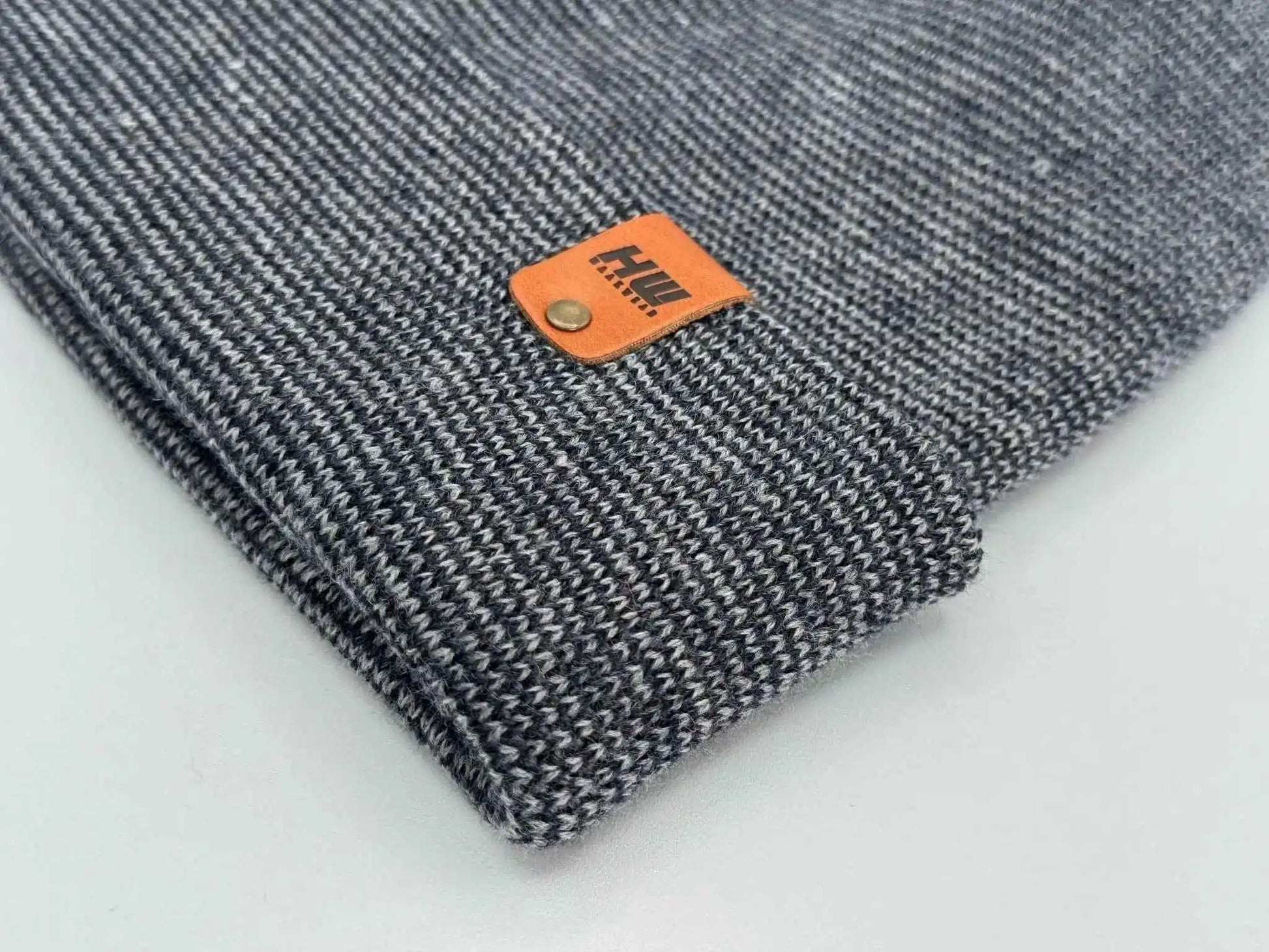 Gray knit beanie close-up with orange logo patch