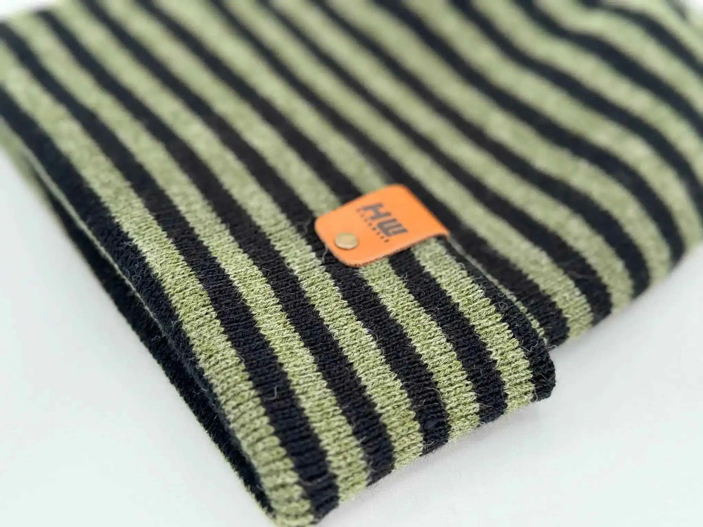 Cuffed striped knit beanie with orange sewn patch label near hem