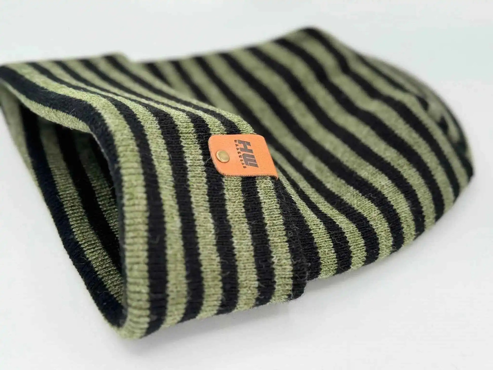 Cuffed knit beanie with black, green, and cream stripes; orange brand label