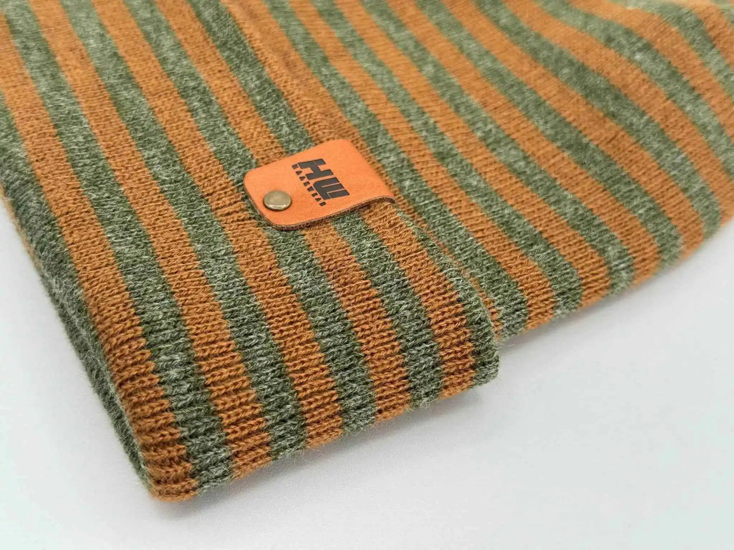 Brown and green striped cuffed beanie close-up of knit texture and leather patch