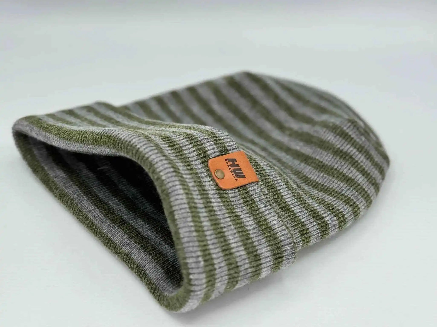 Gray and green striped cuffed beanie, rolled edge opening with orange logo patch