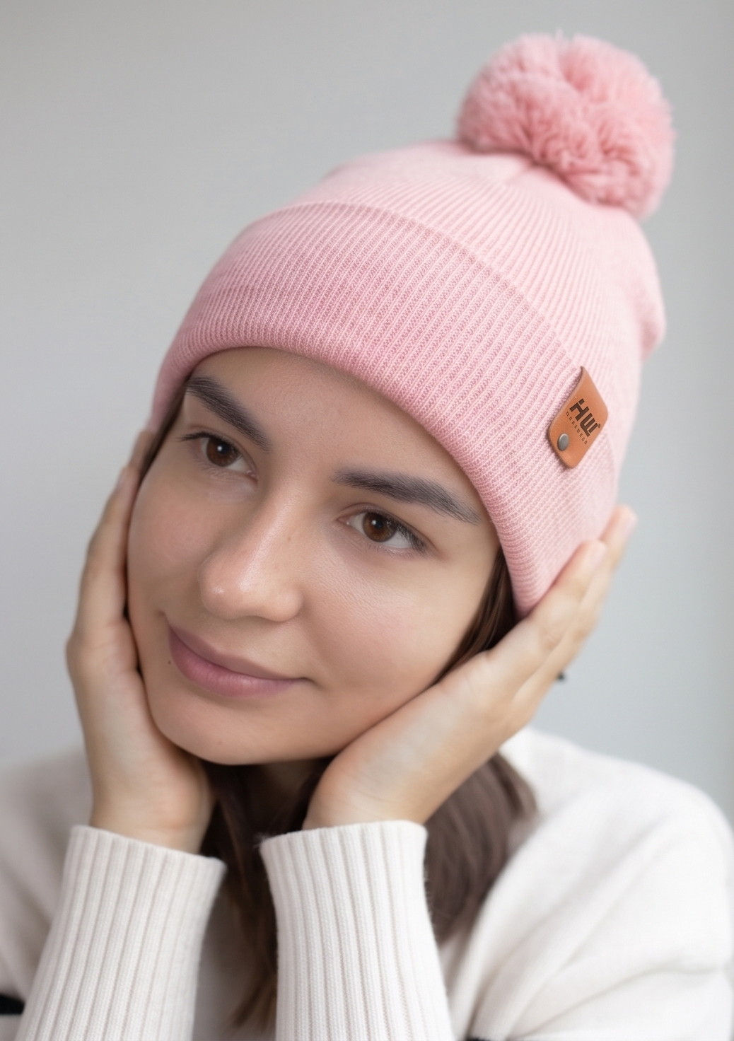 Pearl pink ribbed knit beanie with folded cuff, pom pom, and logo patch