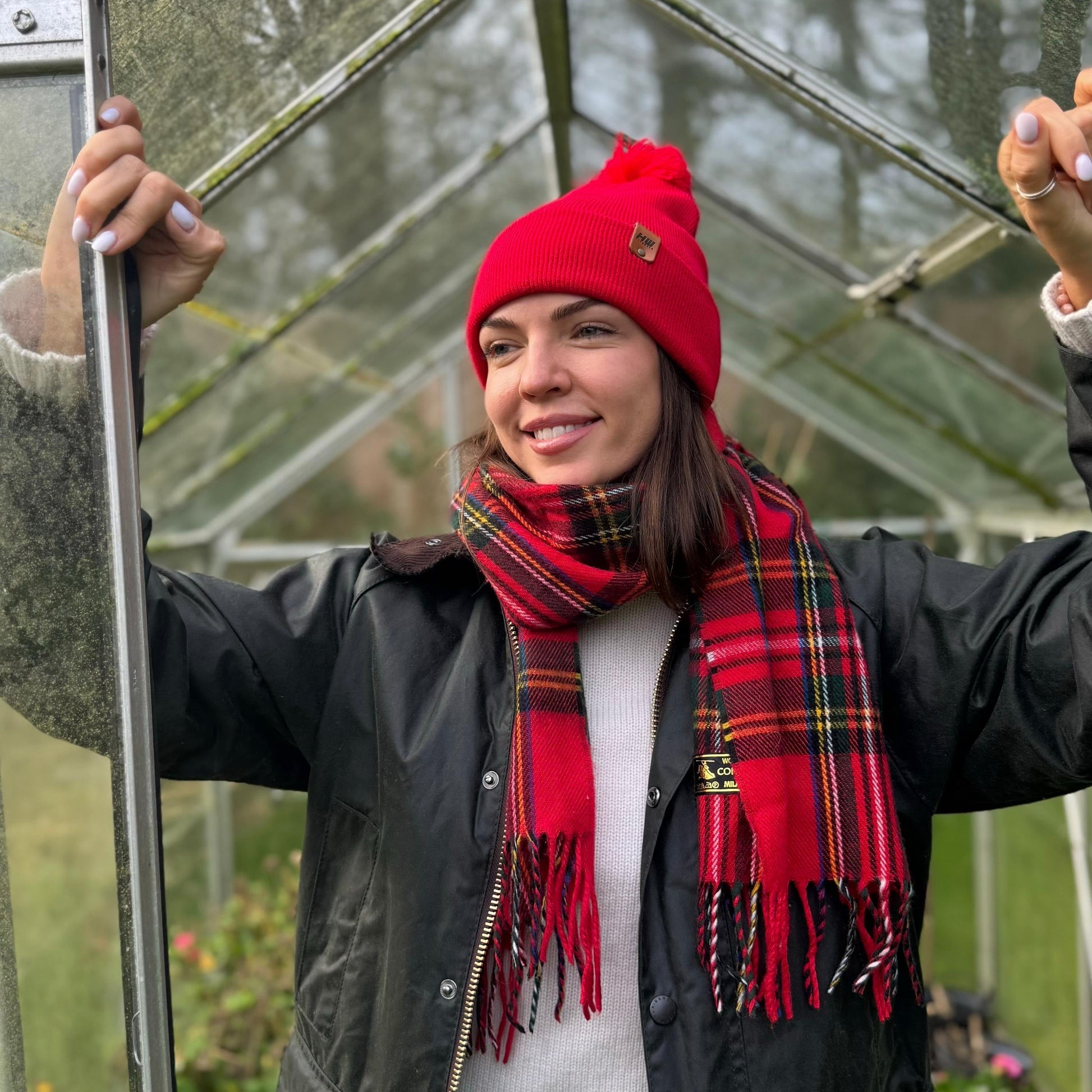 Red knit beanie with pom pom and folded cuff, styled with plaid scarf