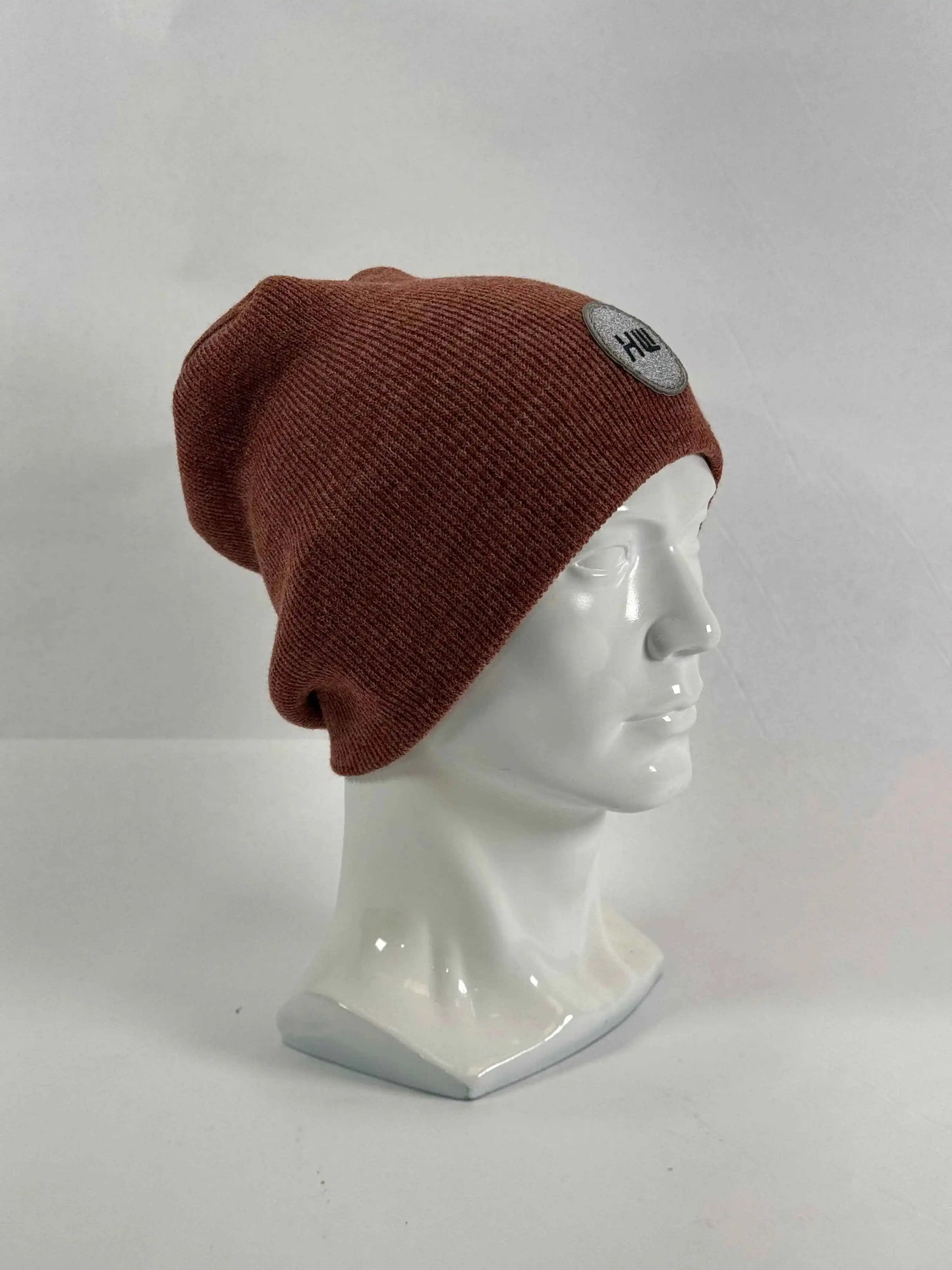 Burgundy knit beanie on mannequin, uncuffed fit, stitched logo patch on side