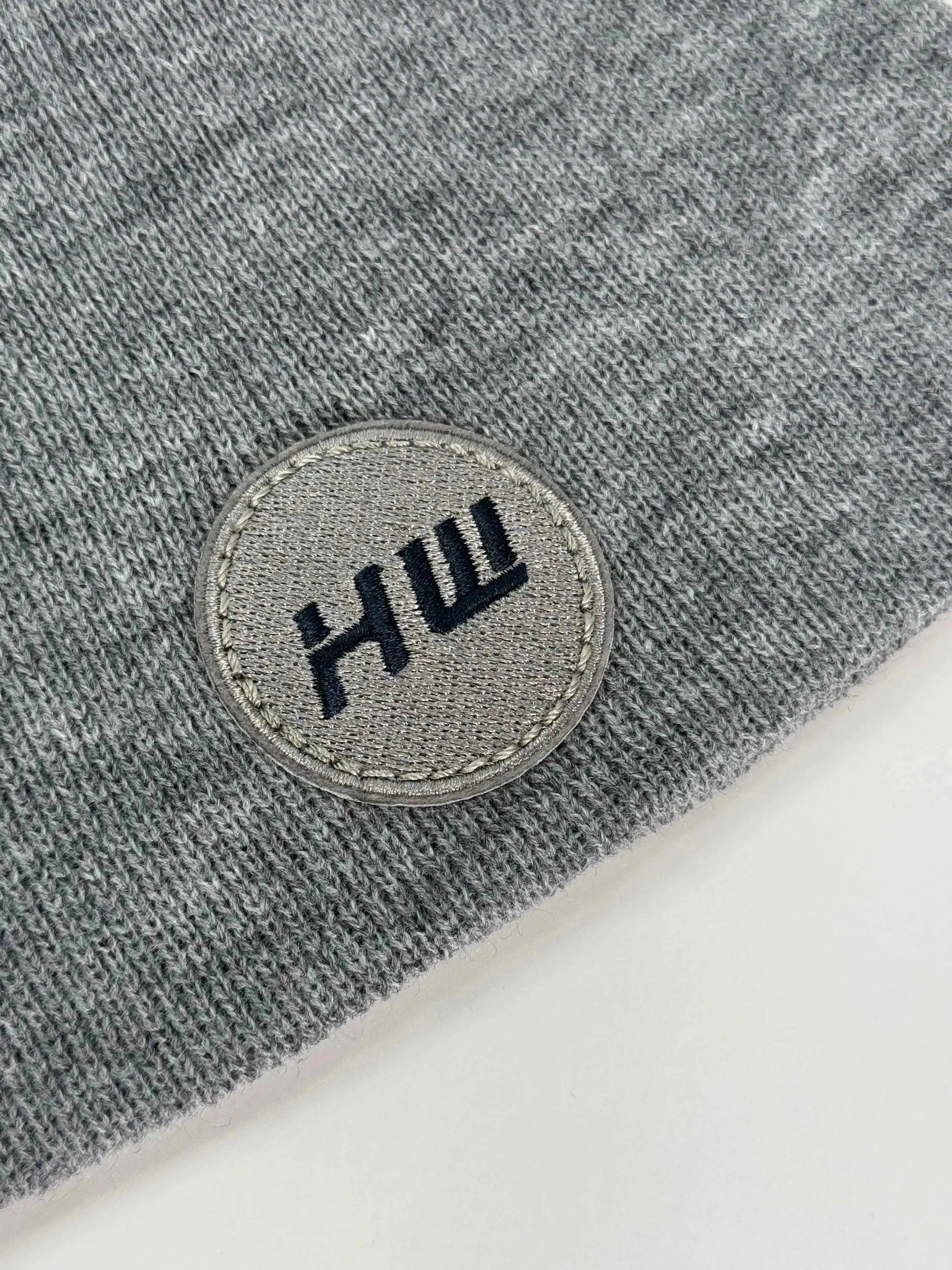 Gray knit beanie with stitched round logo patch on the cuff