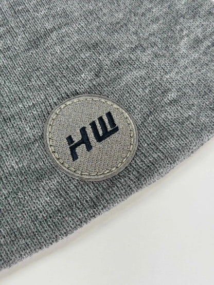 Gray knit beanie with stitched round logo patch on the cuff
