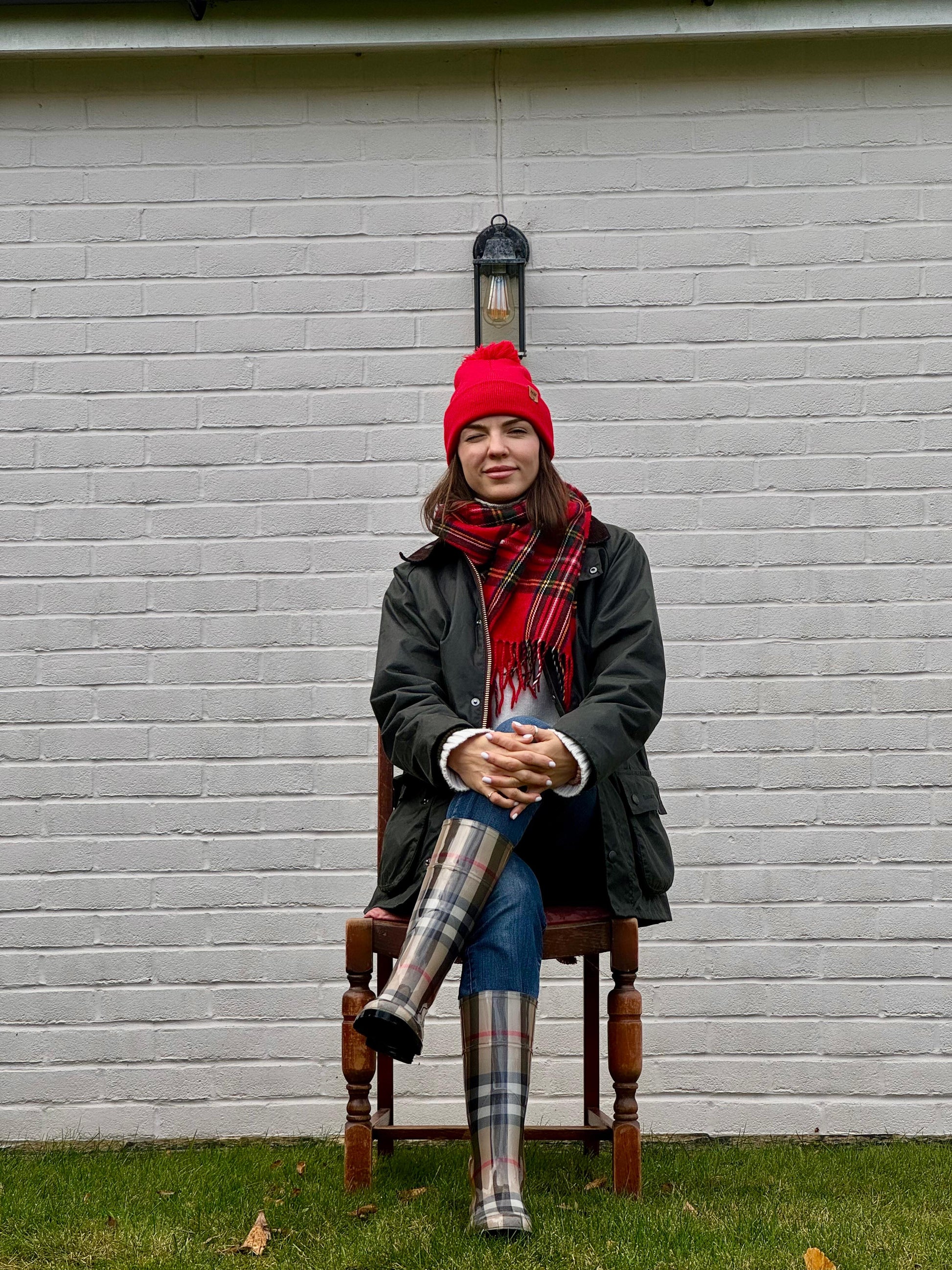 Red pom pom beanie with folded cuff, worn with plaid scarf and coat