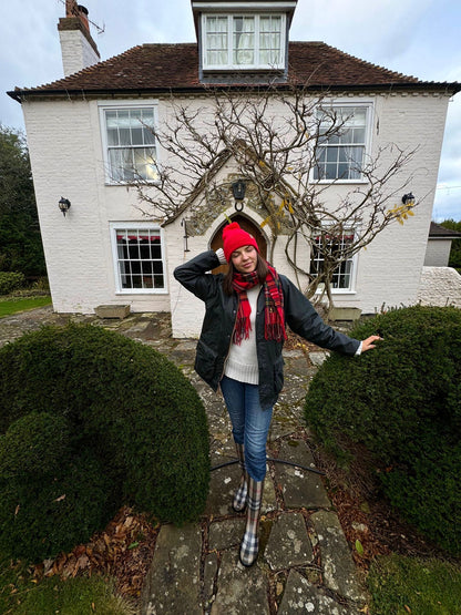 Red pom pom beanie with folded cuff, worn outdoors in winter clothing