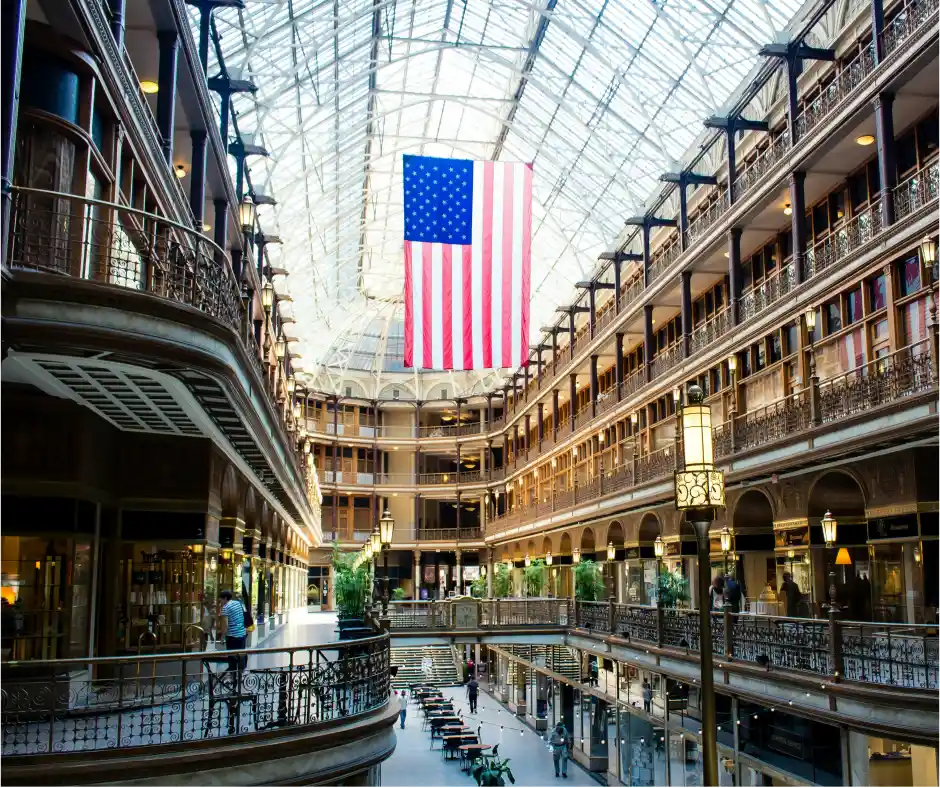 Large American flag hanging from a high ceiling in a multi-story building with glass walls in downtown Cleveland  ohio, arcade, world first mall. 